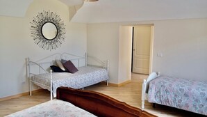 Une chambre avec deux lits, un miroir, une porte et un luminaire au plafond.