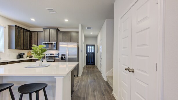 A modern kitchen with a central island, stainless steel appliances, and a hallway leading to a door. - Sleeps 18 5BR Walden Home Near Lake Conroe & Margaritaville (Montgomery)