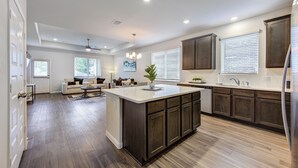 A spacious kitchen with dark wood cabinets, a central island, and a dining area with a sofa and chairs. - Sleeps 18 5BR Walden Home Near Lake Conroe & Margaritaville (Montgomery)