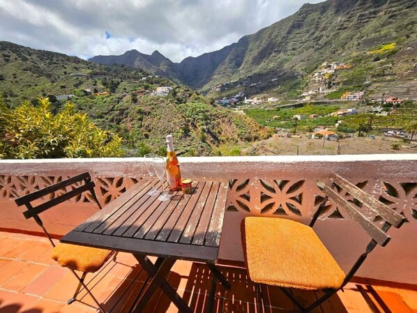 Une terrasse avec une table et des chaises, offrant une vue sur un paysage montagneux.