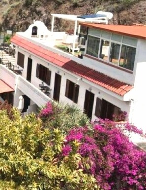 A building with a red-tiled roof, white walls, and a balcony.