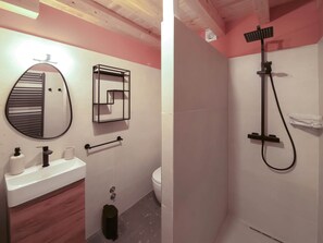 Un baño con un espejo redondo, un perchero, un inodoro y una ducha.