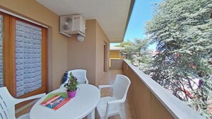Varanda com mesa, cadeiras, um vaso de planta e um aparelho de ar condicionado.