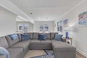 A modern living room with a grey sectional sofa, a patterned rug, and a small side table with a clock.