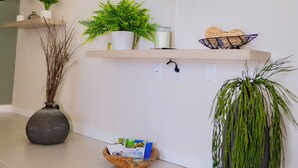 Ein Wohnzimmer mit einem an der Wand befestigten Flachbildfernseher, Holzregalen mit Pflanzen und Dekoration sowie einem großen Topf mit einer Pflanze im Vordergrund.