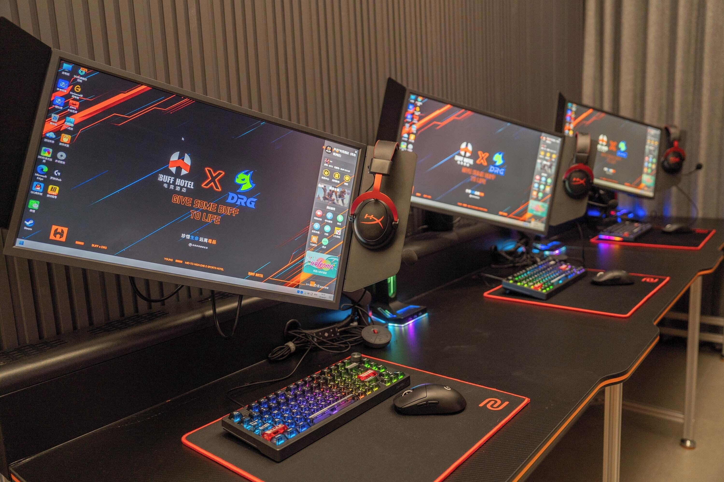 Drie game stations met monitoren, toetsenborden en muizen, elk met een hoofdtelefoon en verlicht door RGB-verlichting.