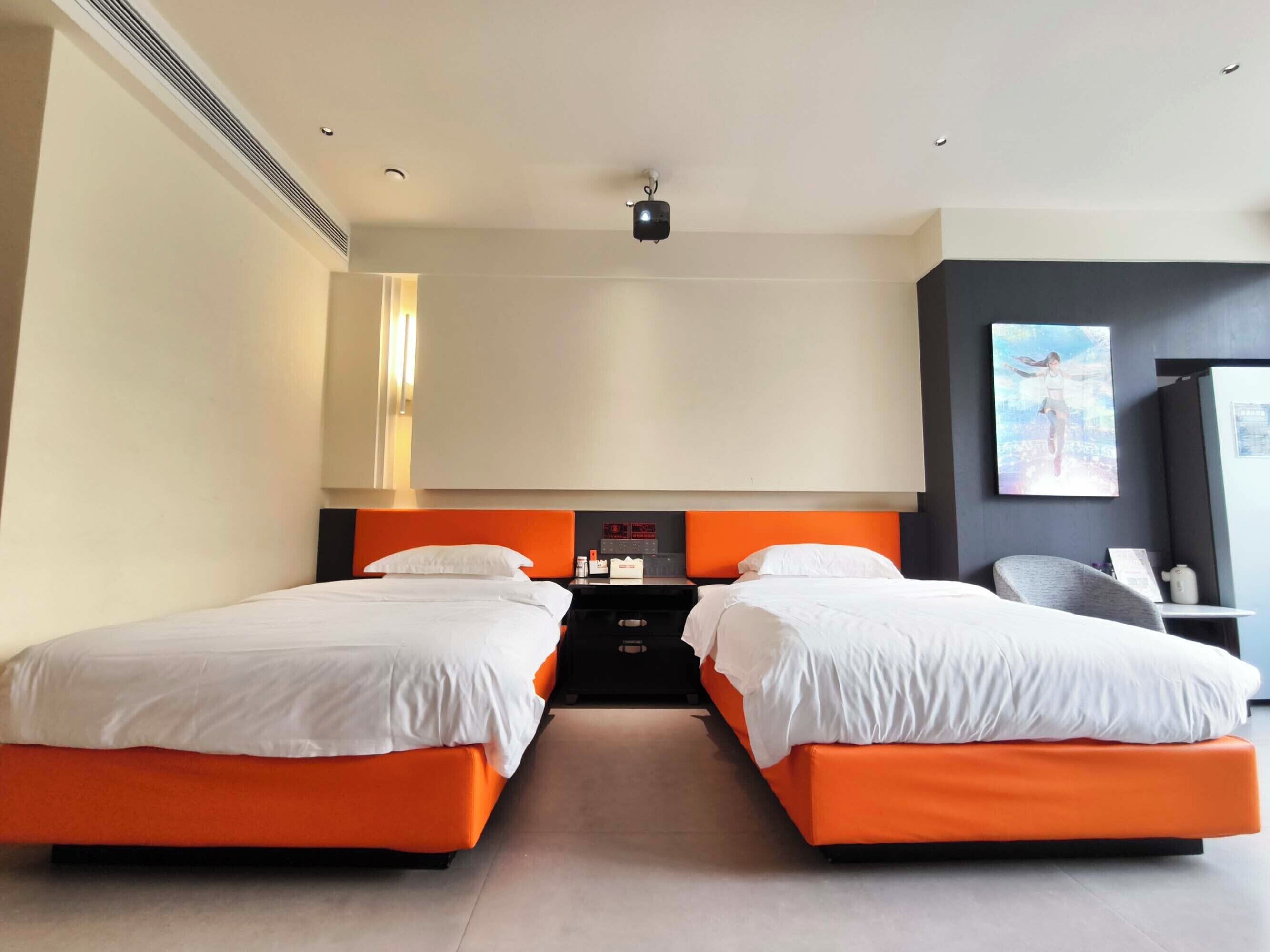 A hotel room with two beds, a flat-screen TV, a desk, and a chair.