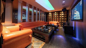 Un espace de détente moderne avec des canapés en cuir, une table basse, un grand écran et une bibliothèque.