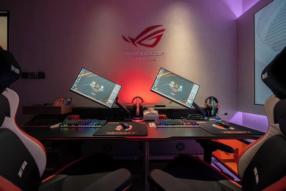 A gaming setup with two monitors, a keyboard, a mouse, and gaming chairs.