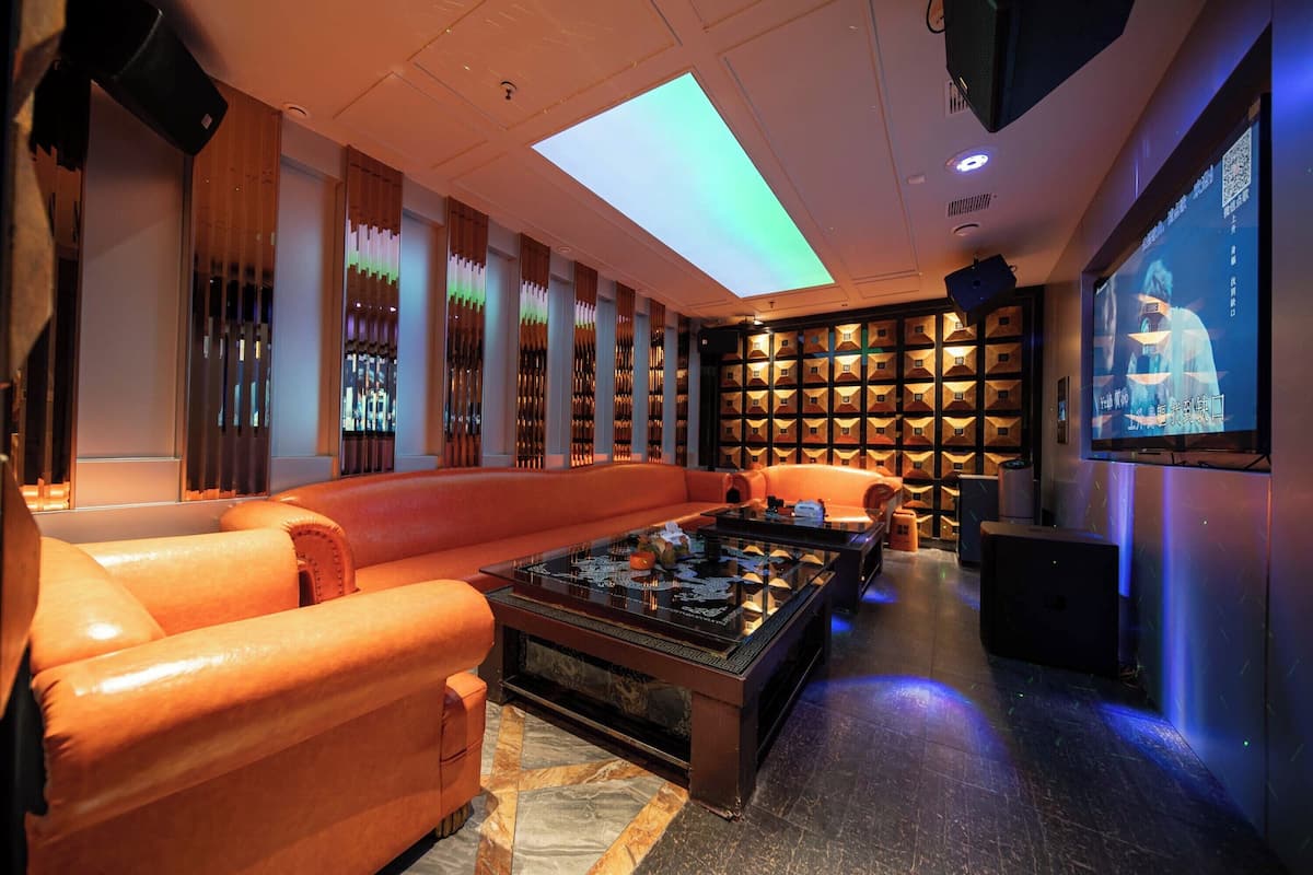 A modern lounge area with leather sofas, a glass coffee table, and a projection screen on the wall.