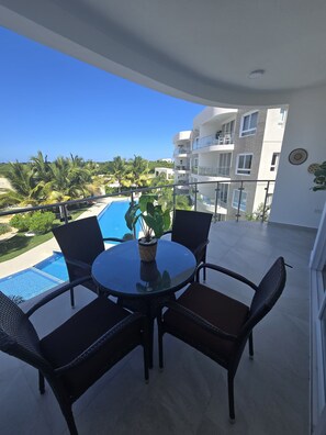 Ein Balkon mit rundem Tisch, Stühlen und einem Blumentopf.
