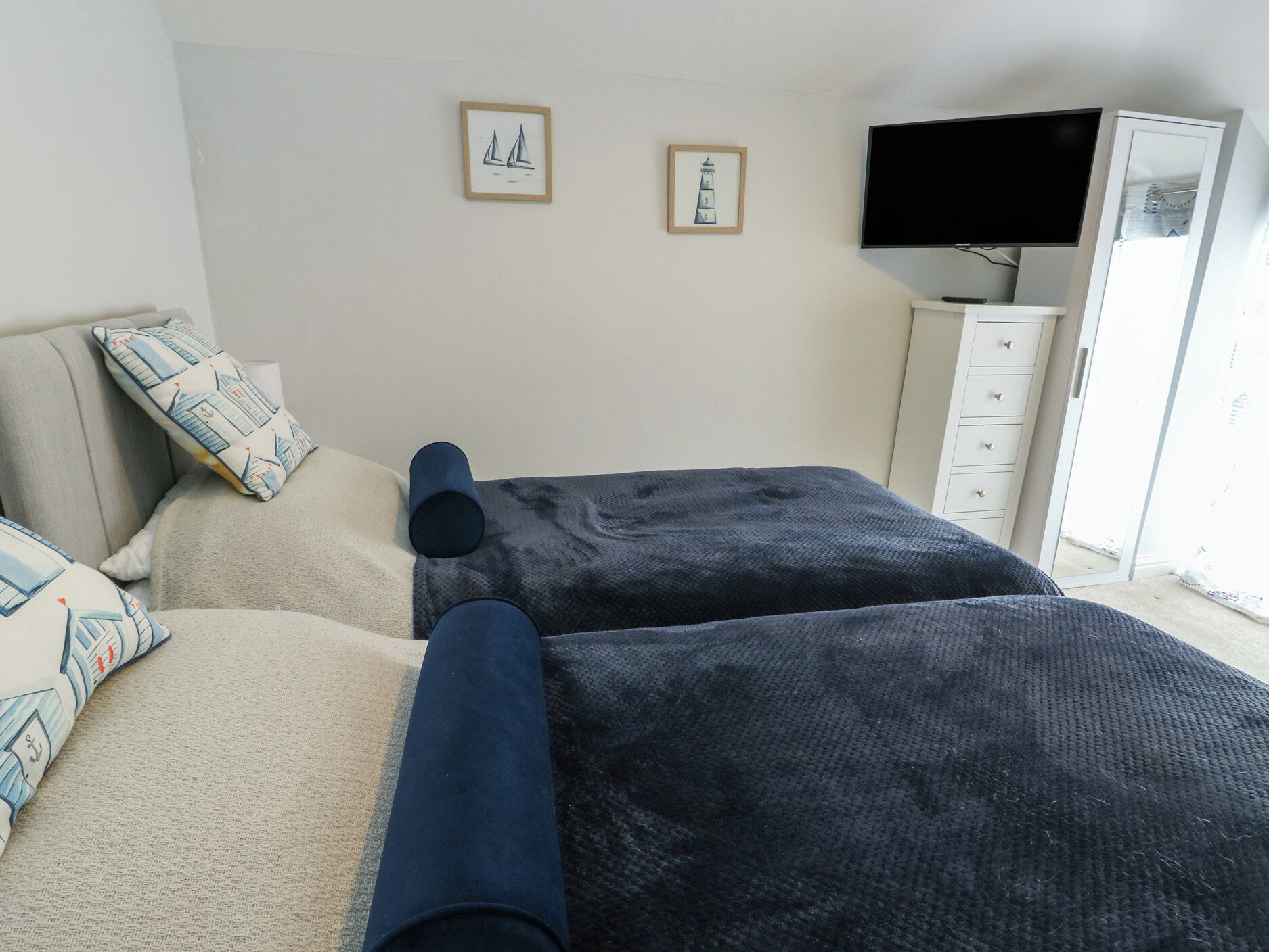 A bedroom with two beds, a TV, and a wardrobe.