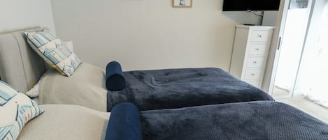 A bedroom with two beds, a TV, and a wardrobe.