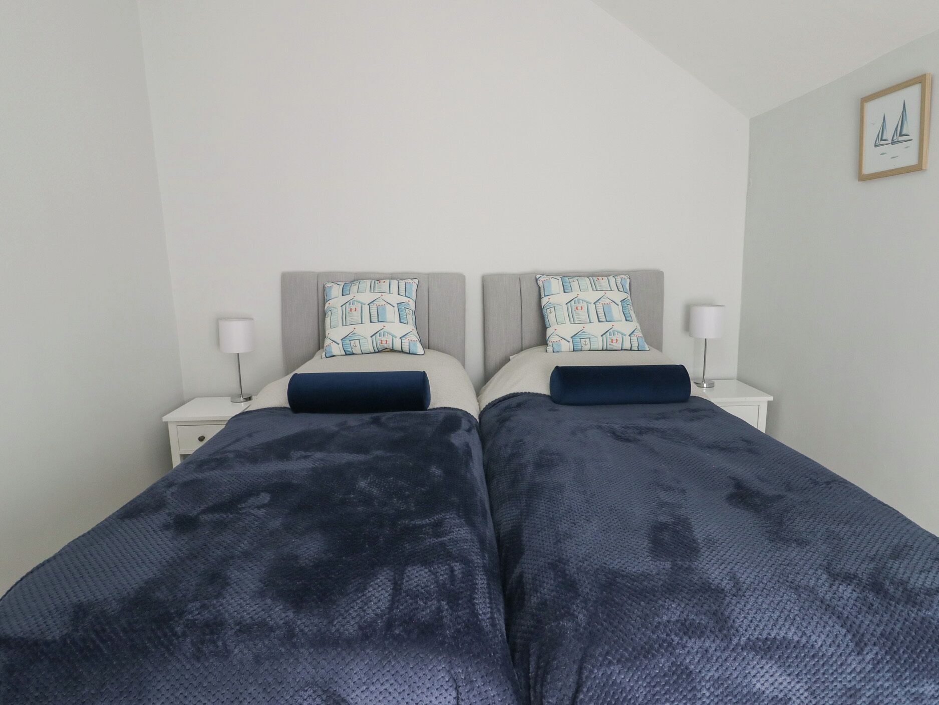 Habitación doble con dos camas, mesitas de noche y lámparas de pared.