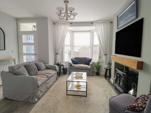A living room with a sofa, a coffee table, a fireplace, and a television. - Bryn Y Mor (Beaumaris)