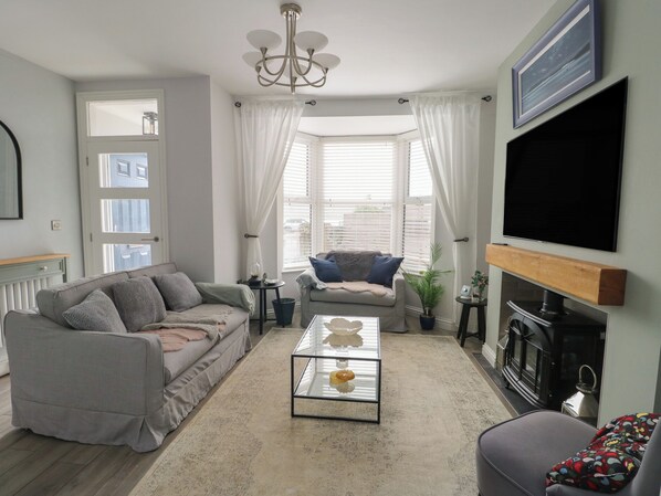 A living room with a sofa, a coffee table, a fireplace, and a television. - Bryn Y Mor (Beaumaris)