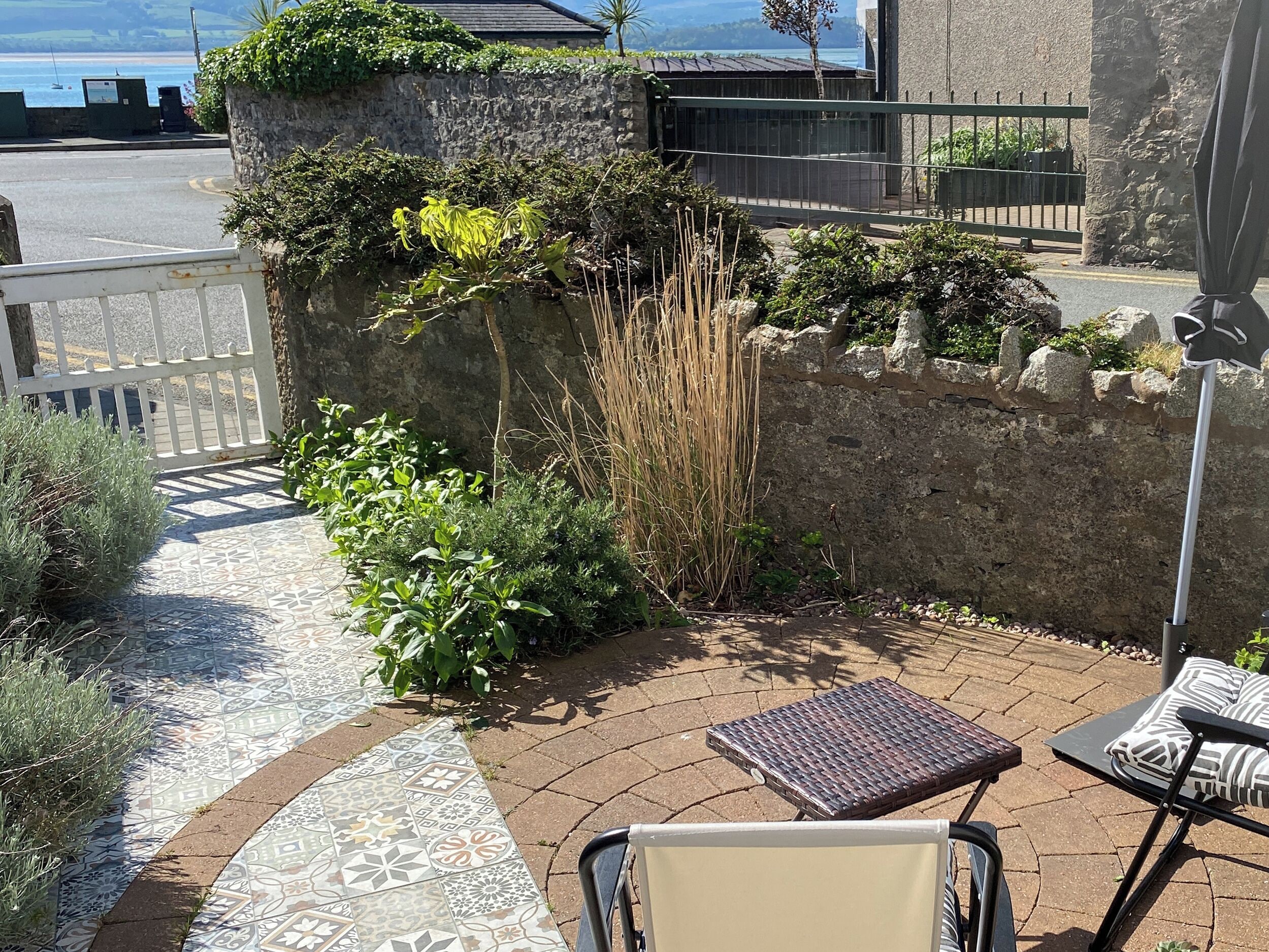 A patio with a patterned tile floor, a metal table, and a chair.