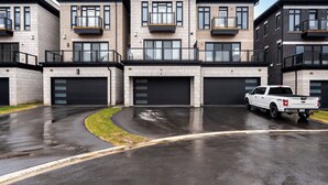 Un edificio residencial moderno de varios pisos con una camioneta blanca estacionada al frente.
