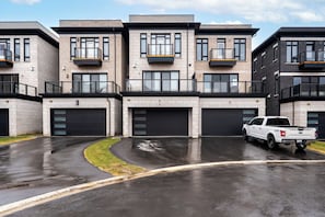 A modern multi-story residential building with a white pickup truck parked in front.
