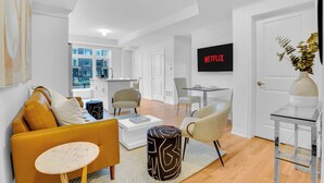 Una sala de estar moderna con un sofá, sillas, una mesa de centro, un televisor y un comedor.
