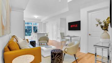 Un salon moderne comprenant un canapé, des fauteuils, une table basse, un téléviseur et un coin repas.