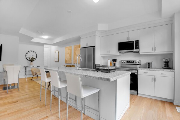 A modern kitchen with white cabinets, stainless steel appliances, and a central island with bar stools.