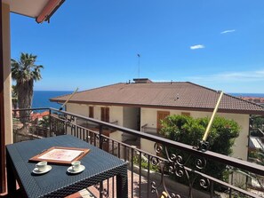 Ein Balkon mit Tisch, einem gerahmten Bild und Blick aufs Meer.