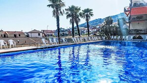 A swimming pool with clear blue water, surrounded by white lounge chairs and palm trees. - Lovely apartment for 4 guests with pool, A/C, WIFI and balcony (Cipressa)