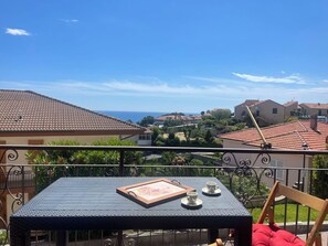 Ein Balkon mit Tisch, zwei Tassen und einem Tablett mit einem Bild.