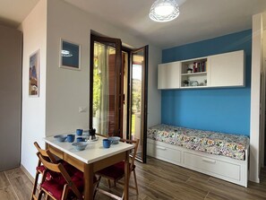 Ein Essbereich mit einem Tisch für zwei Personen, einer Bank mit Blumenkissen und einem weißen Schrank darüber.
