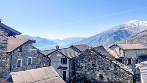 A mountain village with stone buildings, a clear sky, and a snow-capped mountain in the background. - Nice apartment for 4 people with WIFI, TV, balcony and pets allowed (Peglio)