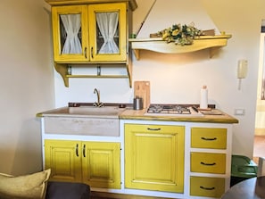 A kitchen with yellow cabinets, a sink, a stove, and a wooden cutting board.