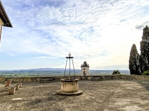 Una terraza en la azotea con una fuente, una pequeña torre de campanas y vistas a colinas distantes.