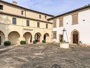 A courtyard with a fountain, arches, and a building with windows and doors. - Nice apartment for 4 guests with WIFI, pool, balcony and panoramic view (Palaia)
