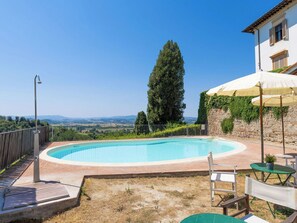 A circular outdoor swimming pool with a clear view of the landscape, a tall tree, and a building with a stone wall. - Nice apartment for 4 guests with WIFI, pool, balcony and panoramic view (Palaia)