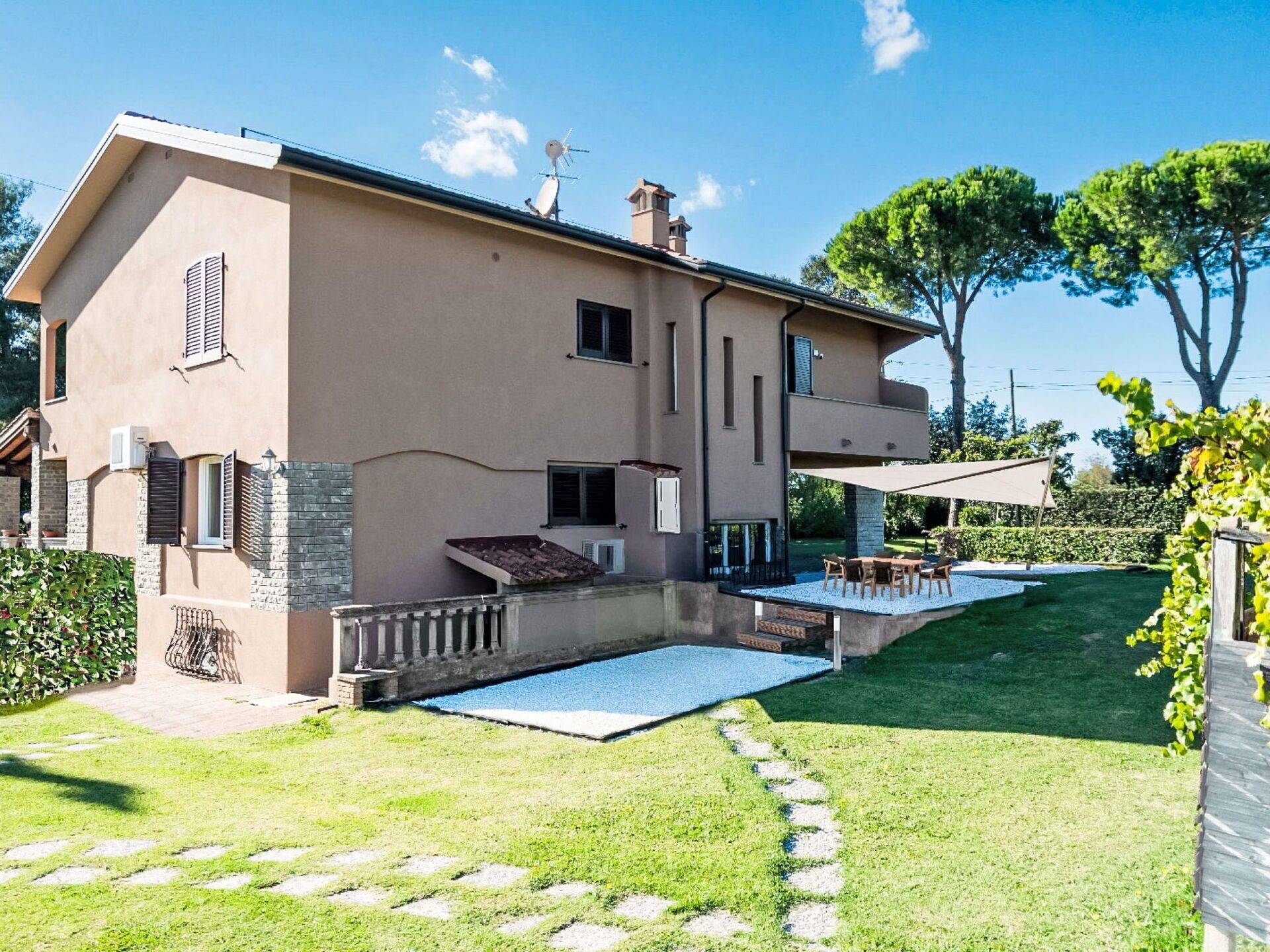 Uma casa de dois andares com um pátio, piscina e jardim.