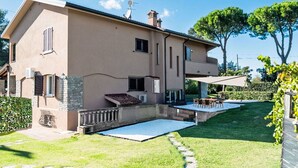 Ein zweigeschossiges Haus mit Terrasse, Swimmingpool und Garten.