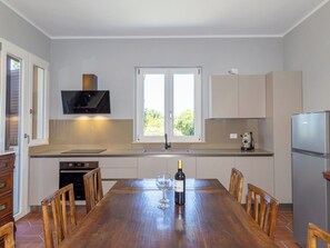 A modern kitchen with a dining table, chairs, a wine bottle, and a TV. - Wonderful private villa for 8 guests with A/C, WIFI, private pool, patio and pets allowed (Montescudaio)