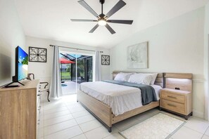 A bedroom with a bed, a desk, a ceiling fan, and a sliding glass door leading to a patio. - Villa Bluegarden- a slice of paradise (Cape Coral)