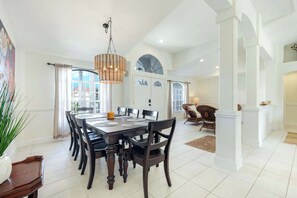 A dining area with a large table, chairs, and a hanging light fixture. - Villa Bluegarden- a slice of paradise (Cape Coral)