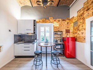 Cucina con mobili bianchi, un frigorifero rosso e una parete decorata con scatole di legno.