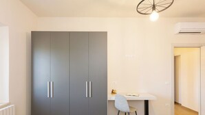 Quarto moderno com um guarda-roupa cinzento, uma pequena escrivaninha com cadeira e um radiador.