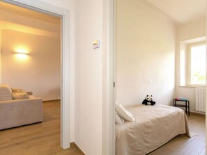 Ein Schlafzimmer mit einem Bett, einem Sofa, einem Panda-Plüschtier, einem Heizkörper und einem Fenster.