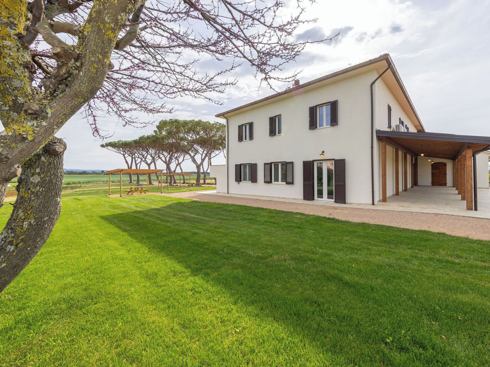 Une maison à deux étages avec un patio couvert, une pelouse et une vue sur la campagne.