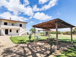 A two-story house with a patio area, a wooden pergola, and a picnic table. - Lovely apartment for 6 people with A/C, WIFI, TV, patio, pets allowed and panoramic view (Castagneto Carducci)