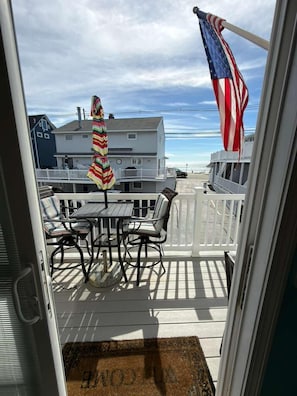 Une terrasse avec une table et des chaises, un parasol à rayures et un drapeau américain.
