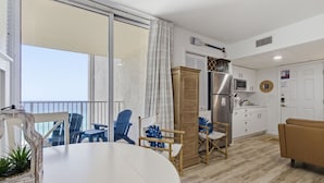 En moderne stue med spisebord, stole, sofa og et køkkenområde med køleskab og skabe.