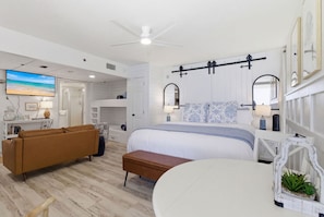A bedroom with a bed, a sofa, a desk, a ceiling fan, and a TV. - Beachfront Condo, King Bed + Bunks | Sleeps 4 | Balcony Gulf Views | Long Beach Resort Tower 1 (Panama City Beach)
