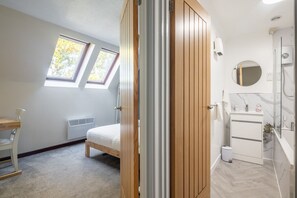 A bedroom with a bed, a desk, a radiator, and a window. - 1Bed Central Apt With Parking! (Cambridgeshire)