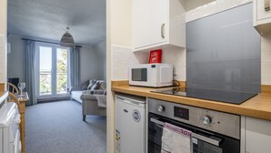 A compact kitchen with a microwave, oven, and a small refrigerator. - 1Bed Central Apt With Parking! (Cambridgeshire)
